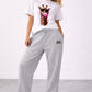 Woman wearing a white t-shirt with a giraffe graphic and gray sweatpants on a plain background